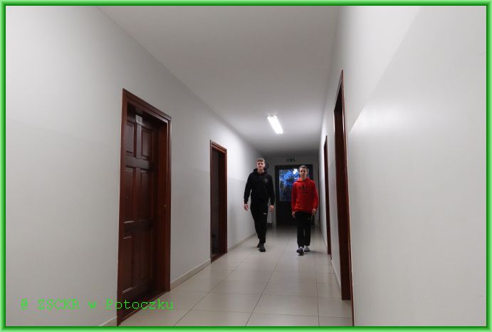 Uczniowie Baran Paweł i Płecha Dawid przechadzają się po szkolnym korytarzu.
